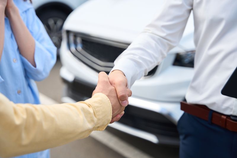customer service manager greets a man at a car dealership